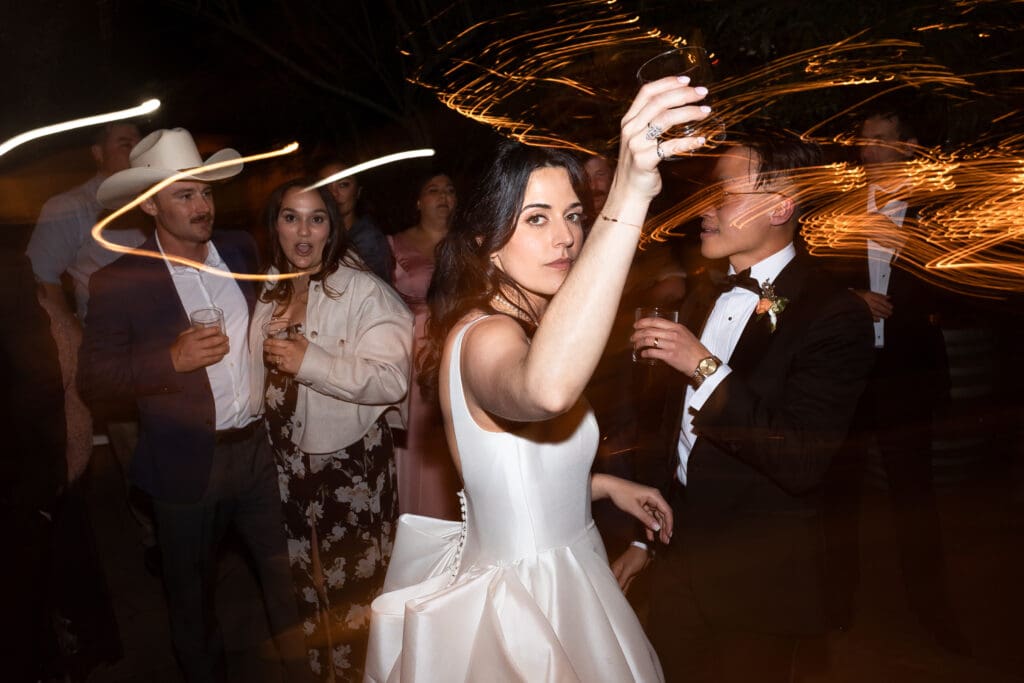 Bride holding up a glass while dancing at wine country wedding
