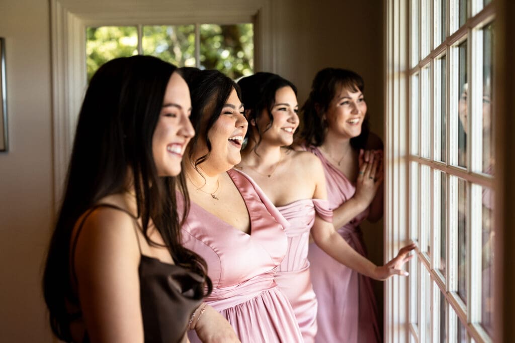 Bridal party smiling and looking out the window at Vine Hill House wedding