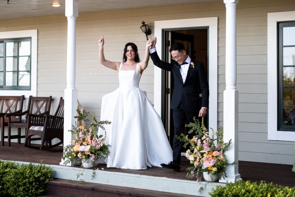 Bride and groom holding hands up excitedly at first announcement after wedding ceremony