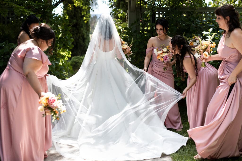 Bridesmaids adjusting bride's dress before wine country wedding