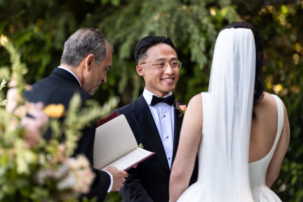 Groom smiling at bride as officiant reads their vows at Sonoma County wedding ceremony