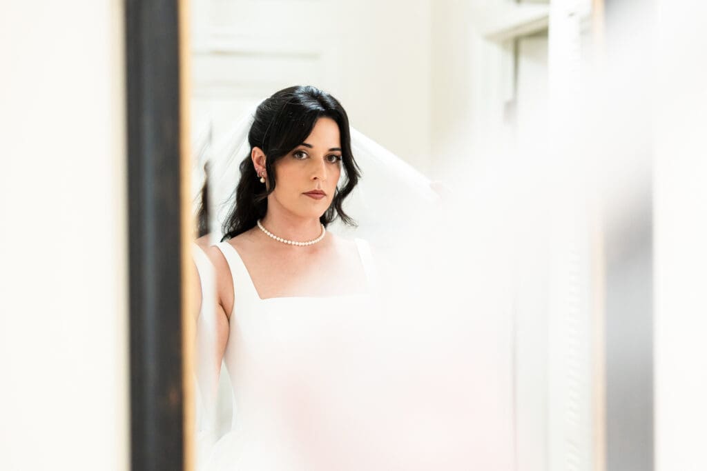 Bride looking at reflection in the mirror before wedding ceremony