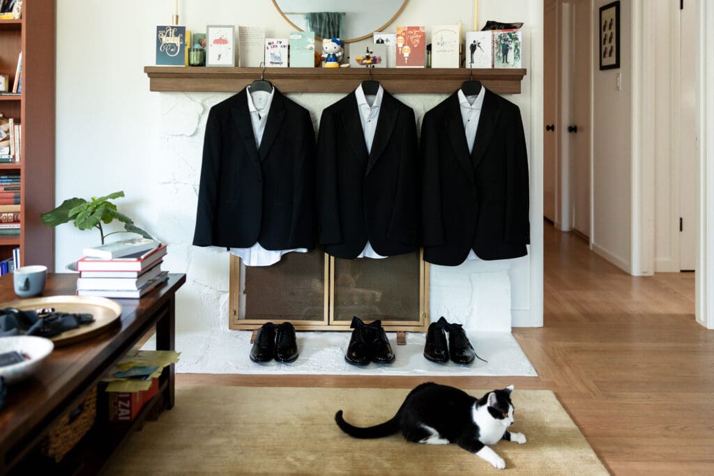 Three tuxedos for Vine Hill House Wedding hung up with cat on the floor