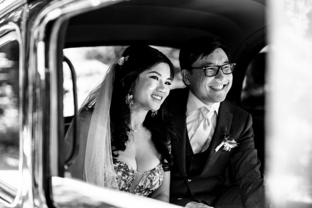 Black and white photo of bride and groom in a car after their wedding reception