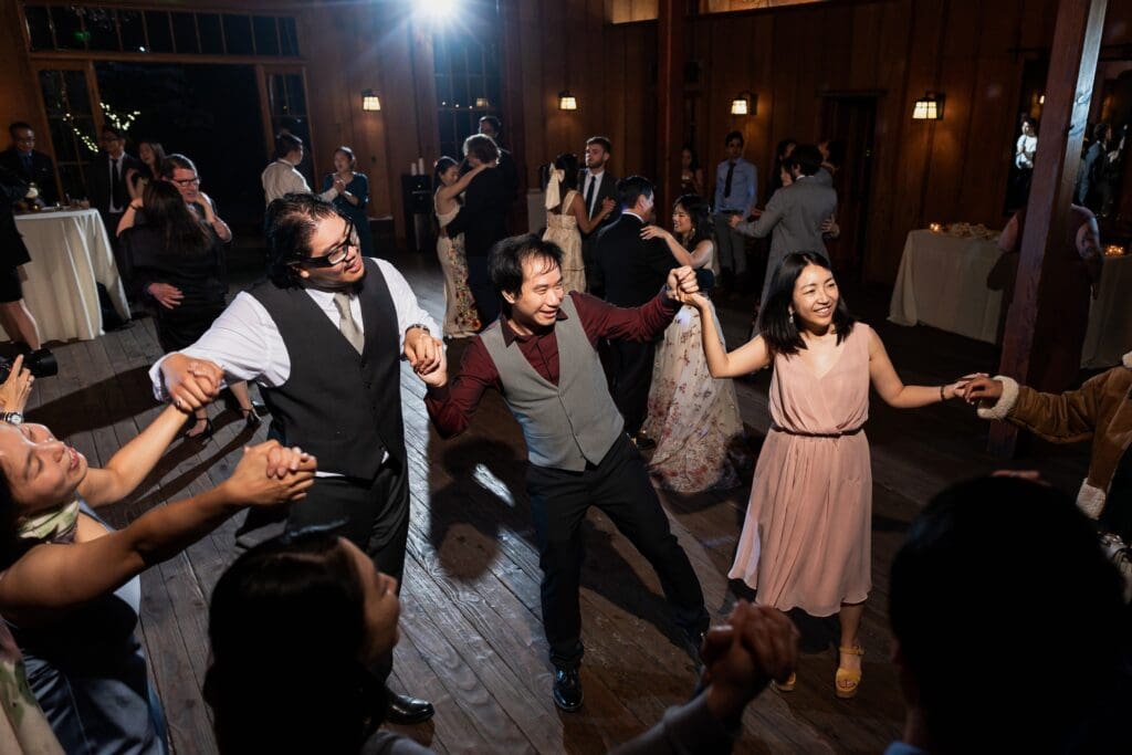Wedding guests holding hands and dancing at wedding reception