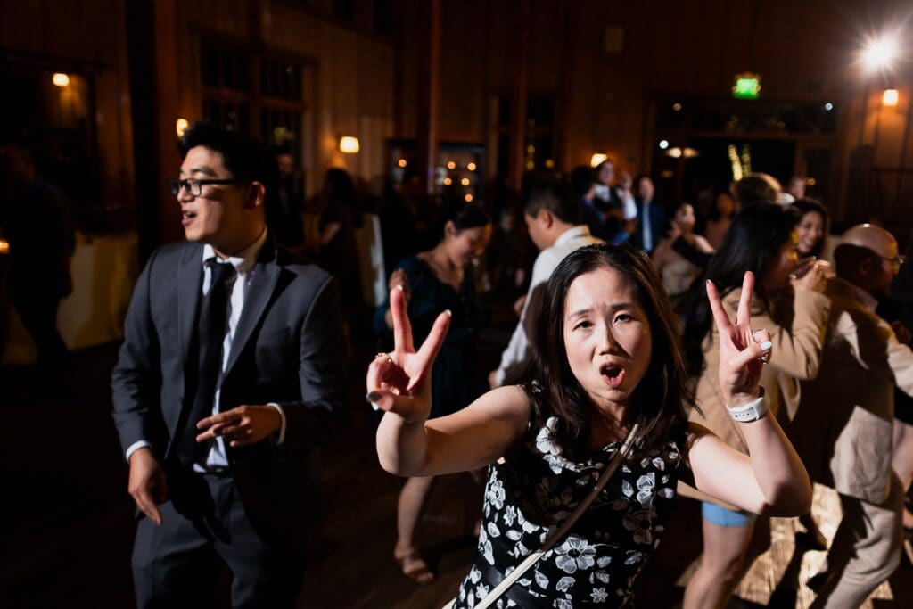 Wedding guests laughing and posing with peace signs at wedding reception