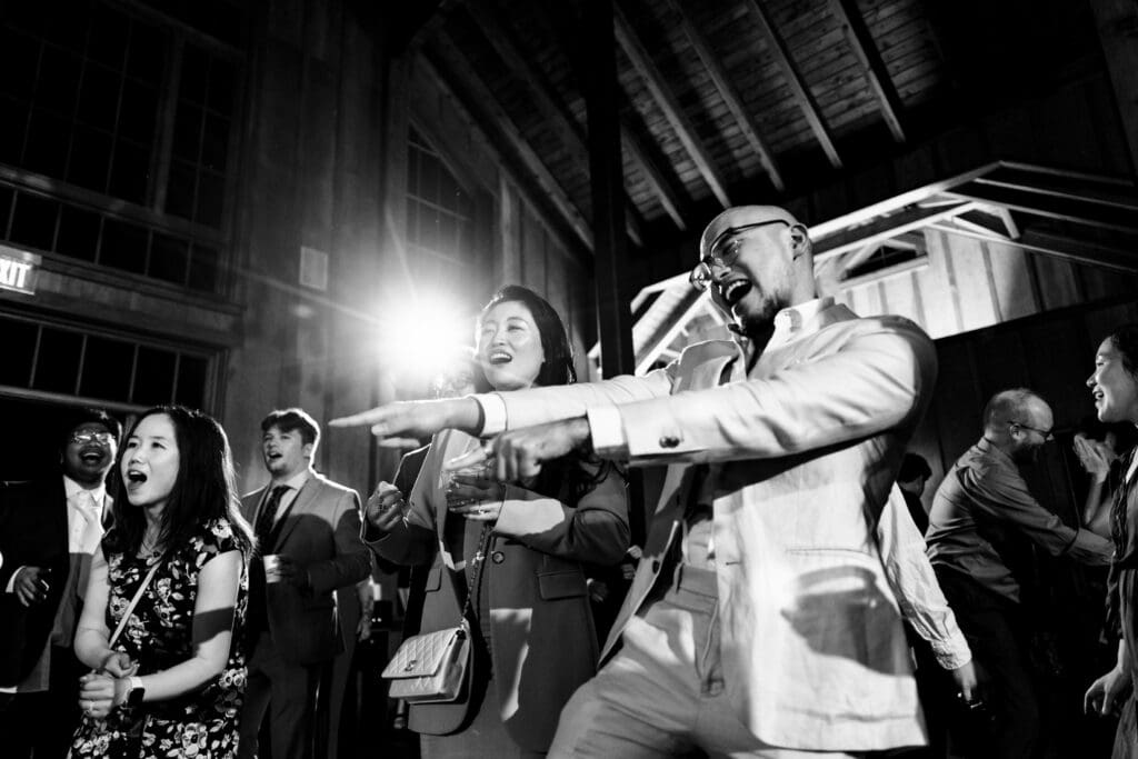 Black and white photo of wedding guests pointing and dancing at Nestldown wedding reception
