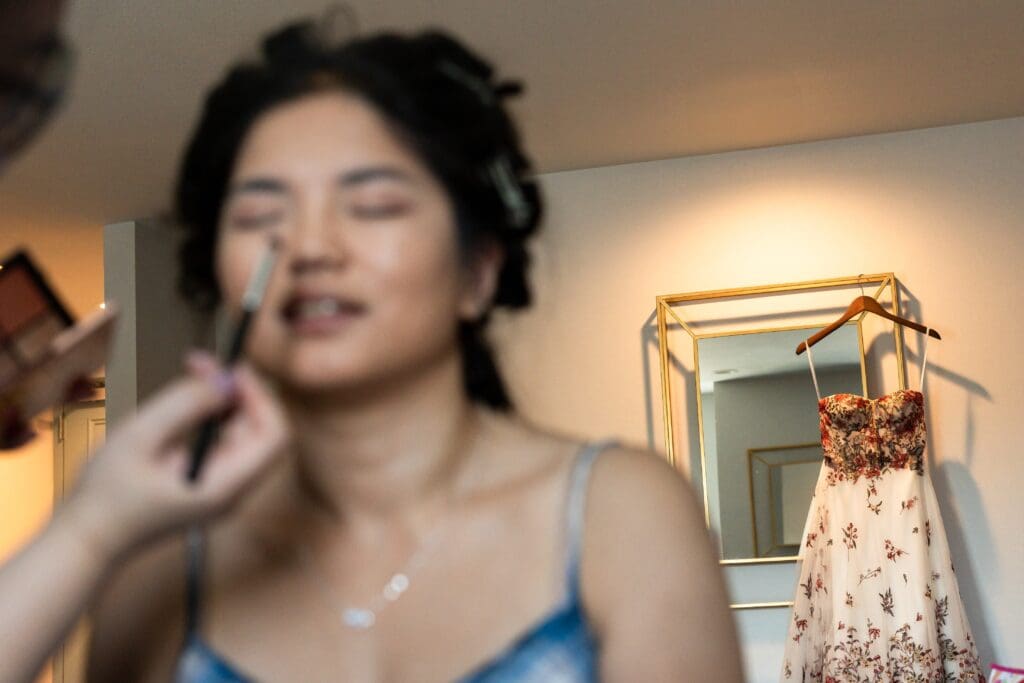 Bride getting ready for Northern California wedding with dress in the background