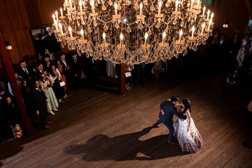 Bride and groom dancing under chandelier at wedding reception first dance