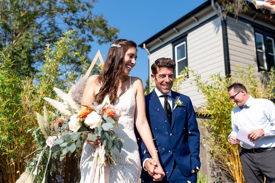 Bride and groom smiling after wedding ceremony as bride holds flower bouquet