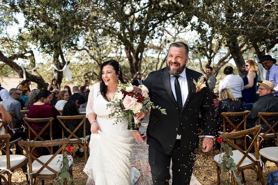 Reception exit of bride and groom as they smile and the bride holds bouquet at Northern California wedding
