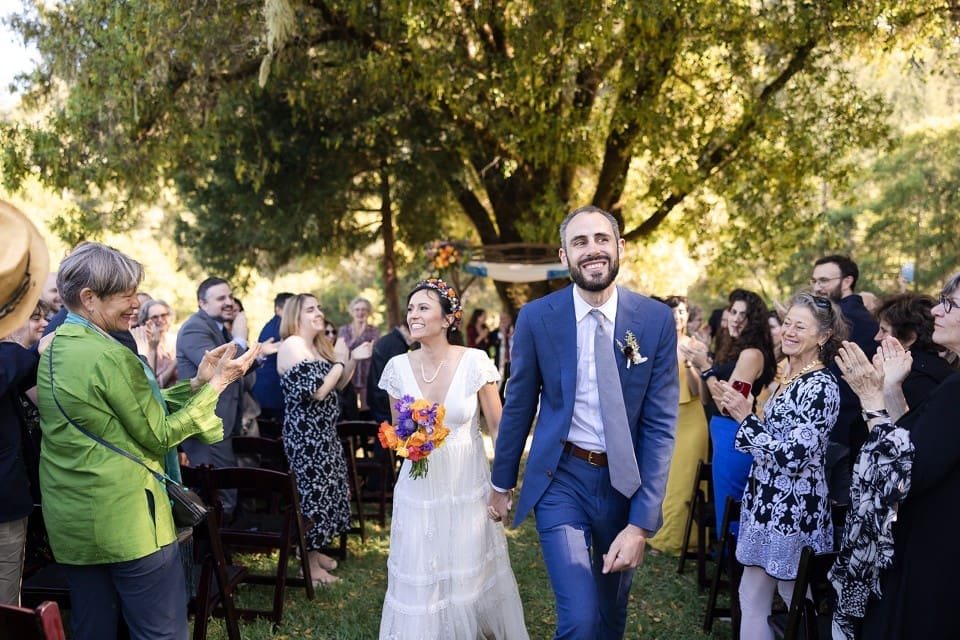 Bride and groom smiling as bride holds colorful bouquet