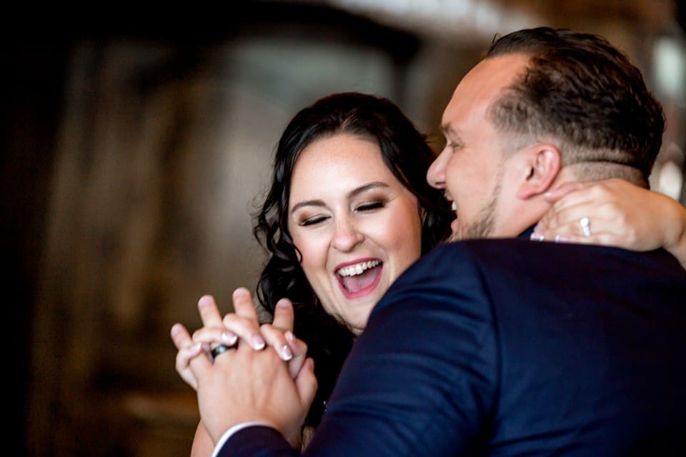 Bride and groom laughing while holding hands for their first dance