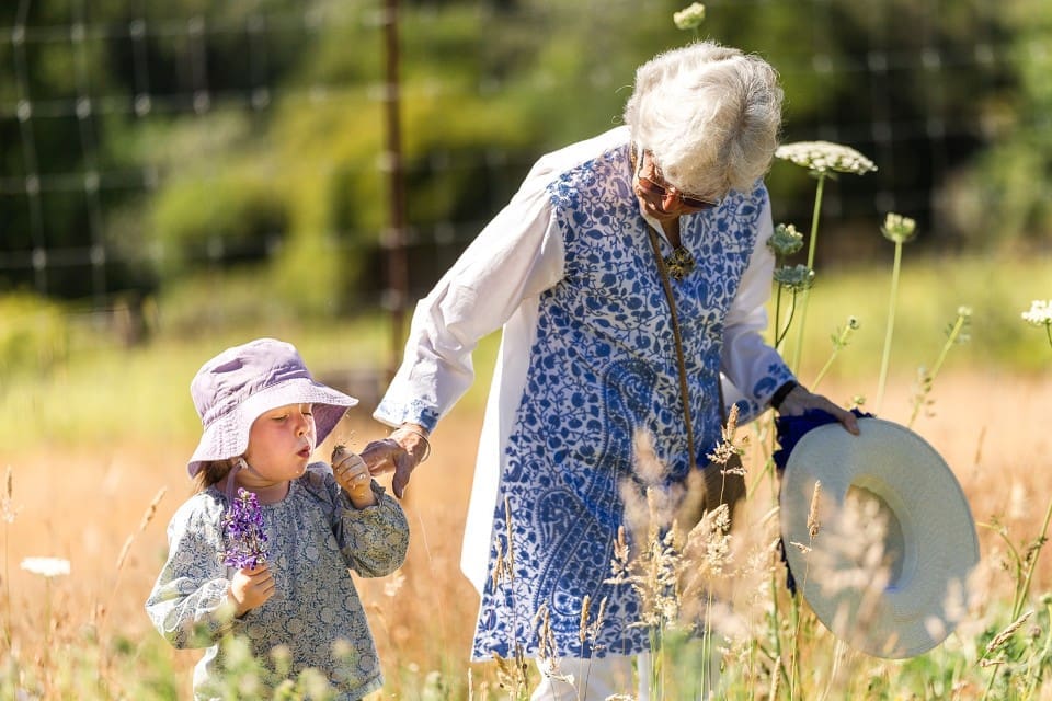 Grandmother walking in flower field with granddaughter before Northern California wedding