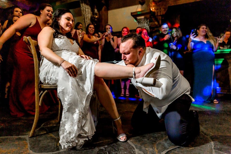 Groom taking garter off wife at wedding reception