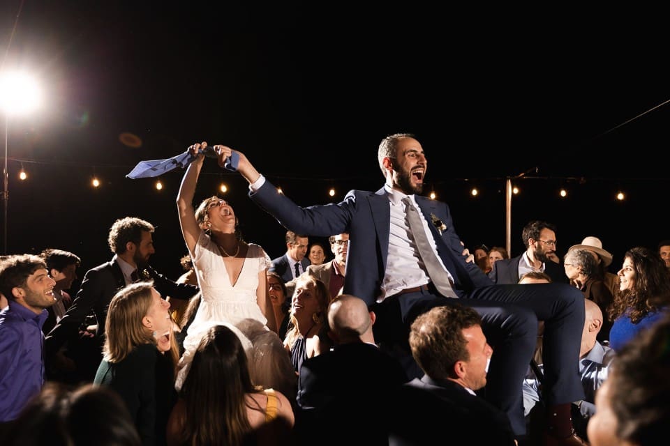 Bride and groom being hoisted up on chairs at wedding reception in Northern California