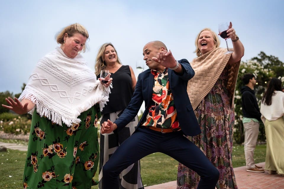 Wedding guests laughing and dancing and drinking wine at wedding reception