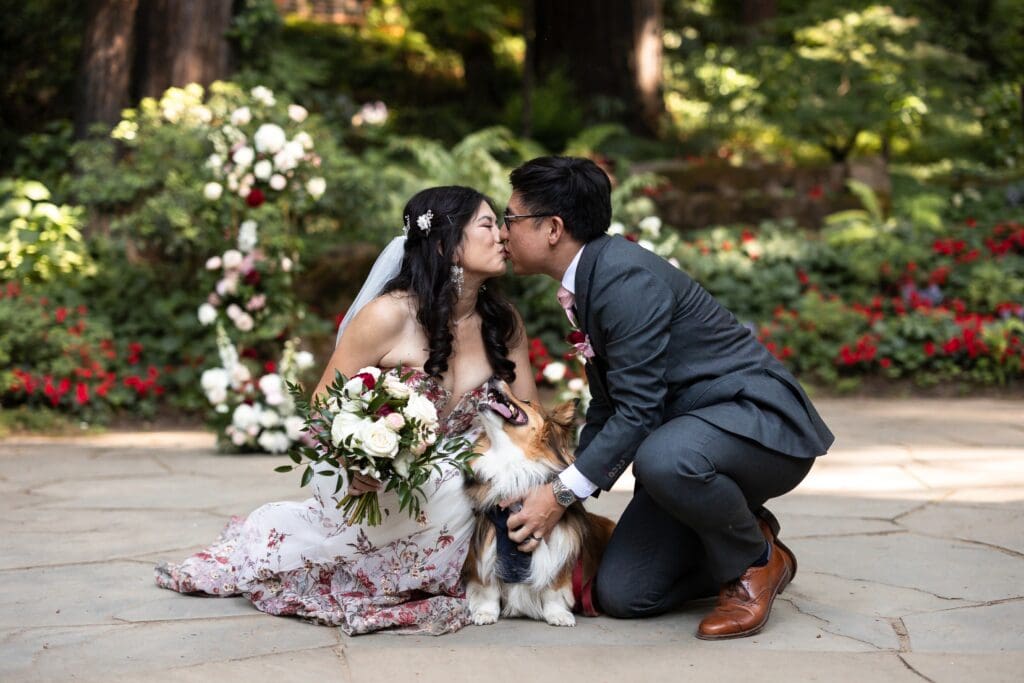 Couple kissing with corgi looking up at them at outdoor wedding ceremony at Nestldown