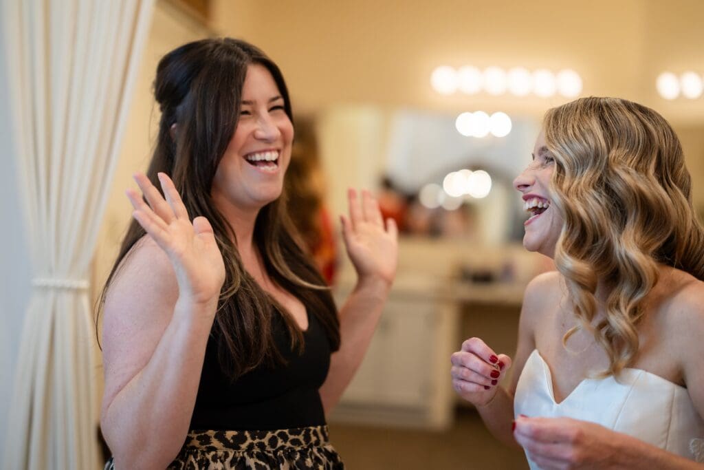 Bride and bridesmaid laughing and smiling in bridal room at Northern California wedding venue