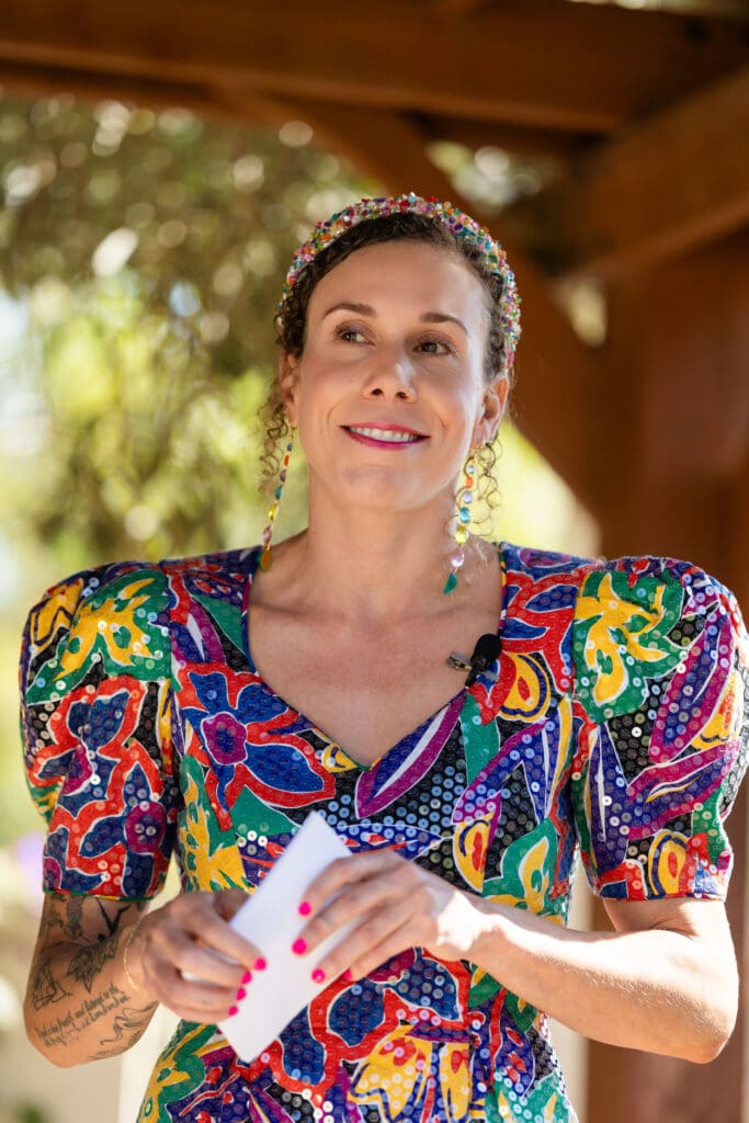 Wedding officiant in beautiful vibrant dress, smiling while holding paper