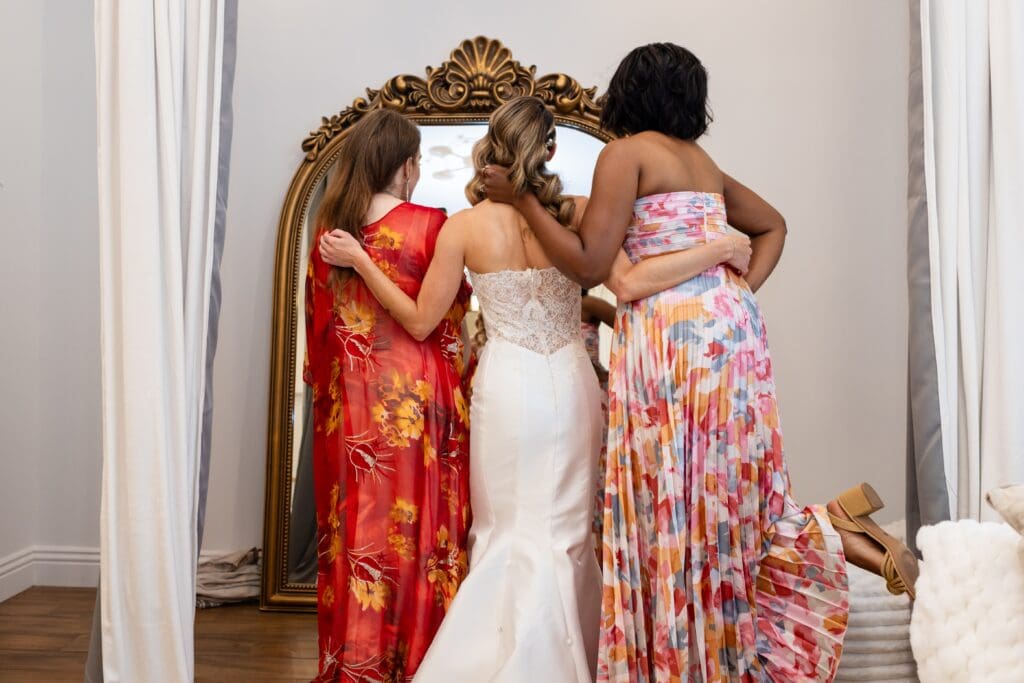 Bride and friends smiling in the mirror in bridal suite at Flying Cloud Farm