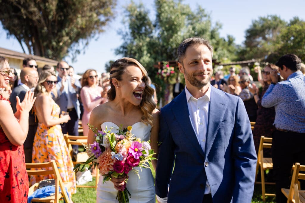 Bride and groom walking down the aisle while bride holds bouquet in Northern California wedding