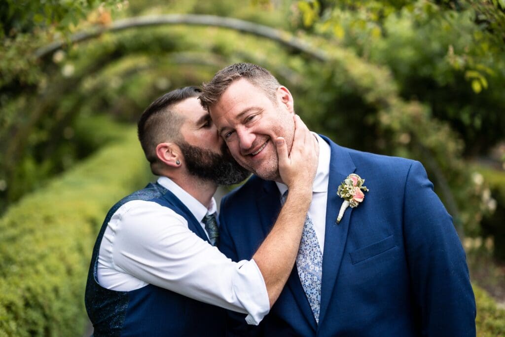 Groom kissing other groom's cheek at Petaluma Wedding Venue