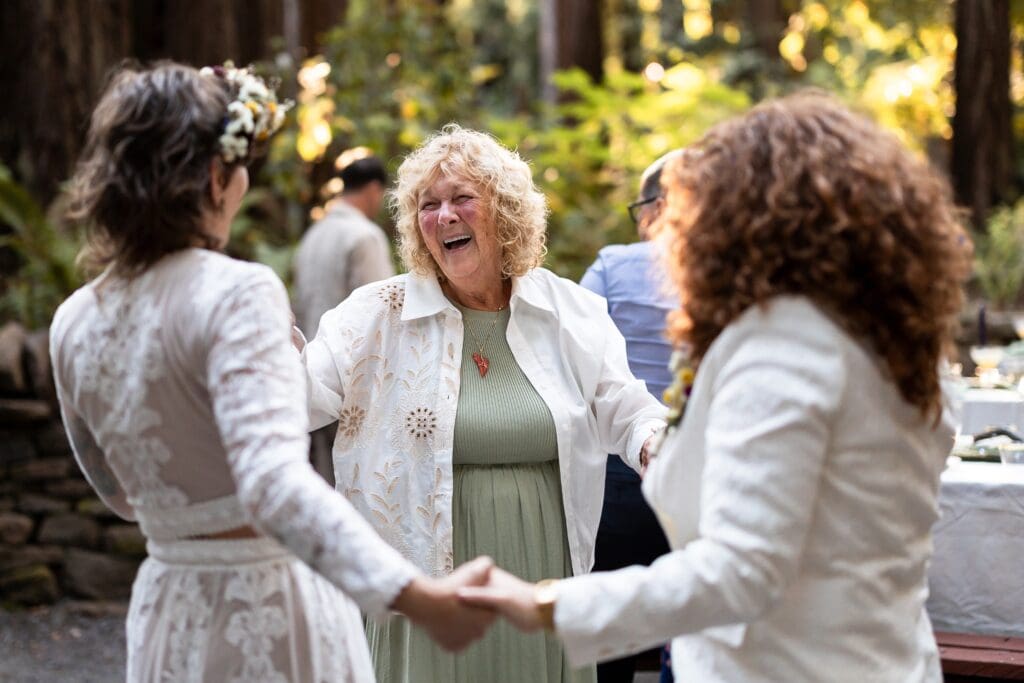Brides holding hands and laughing at Gualala Arts Center wedding