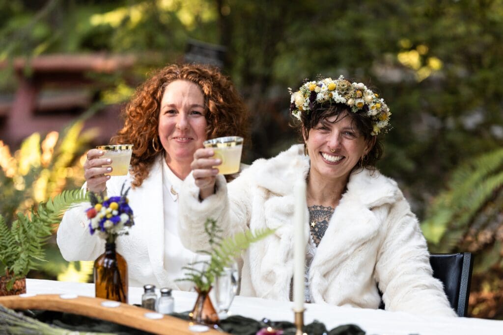 Brides holding up drinks at Gualala wedding reception