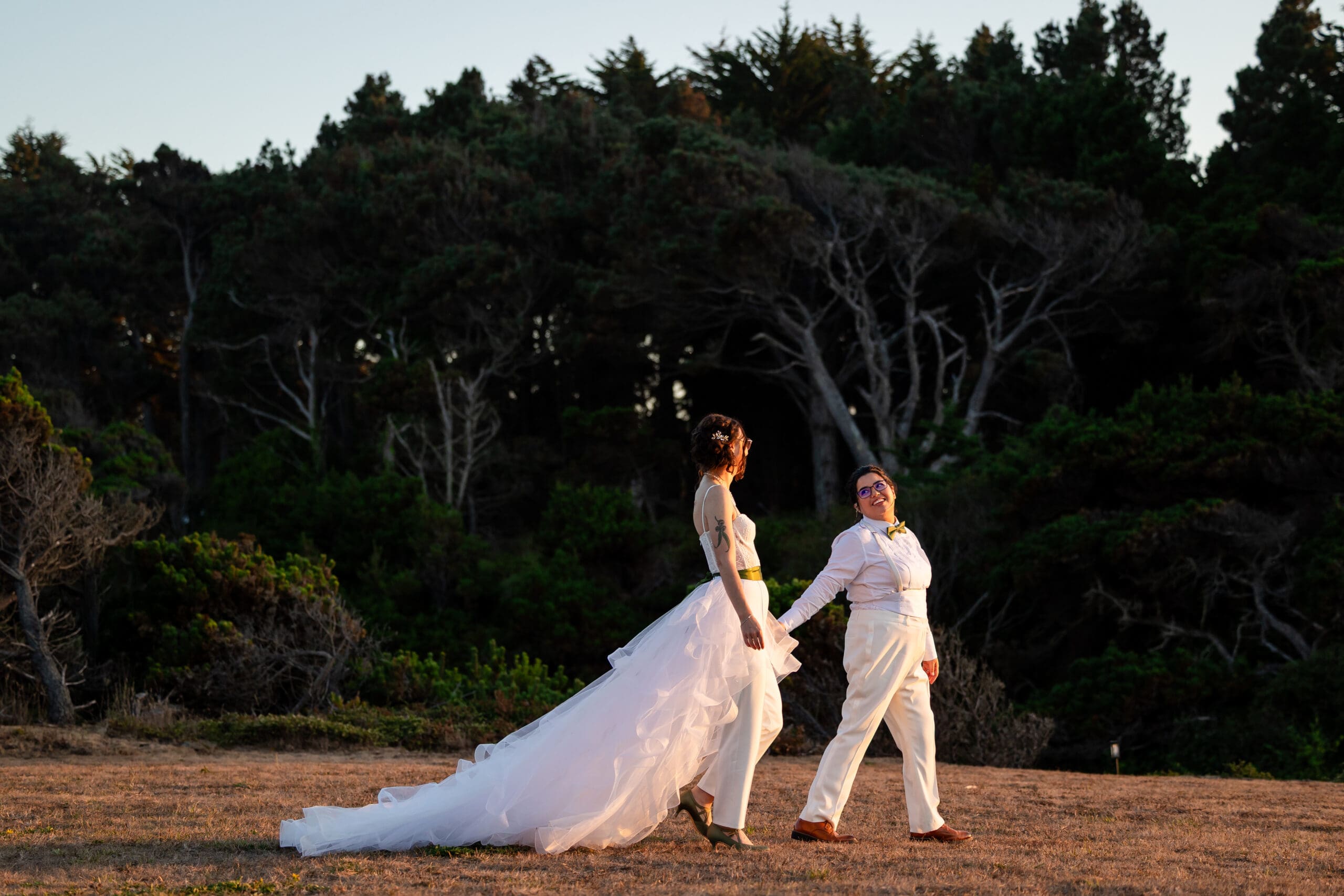 Brides holding hands and walking together on the property of Holly’s Ocean Meadow in Fort Bragg, CA