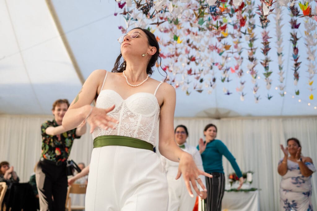 Bride dancing with paper crane display at wedding reception at Holly’s Ocean Meadow in Fort Bragg, CA