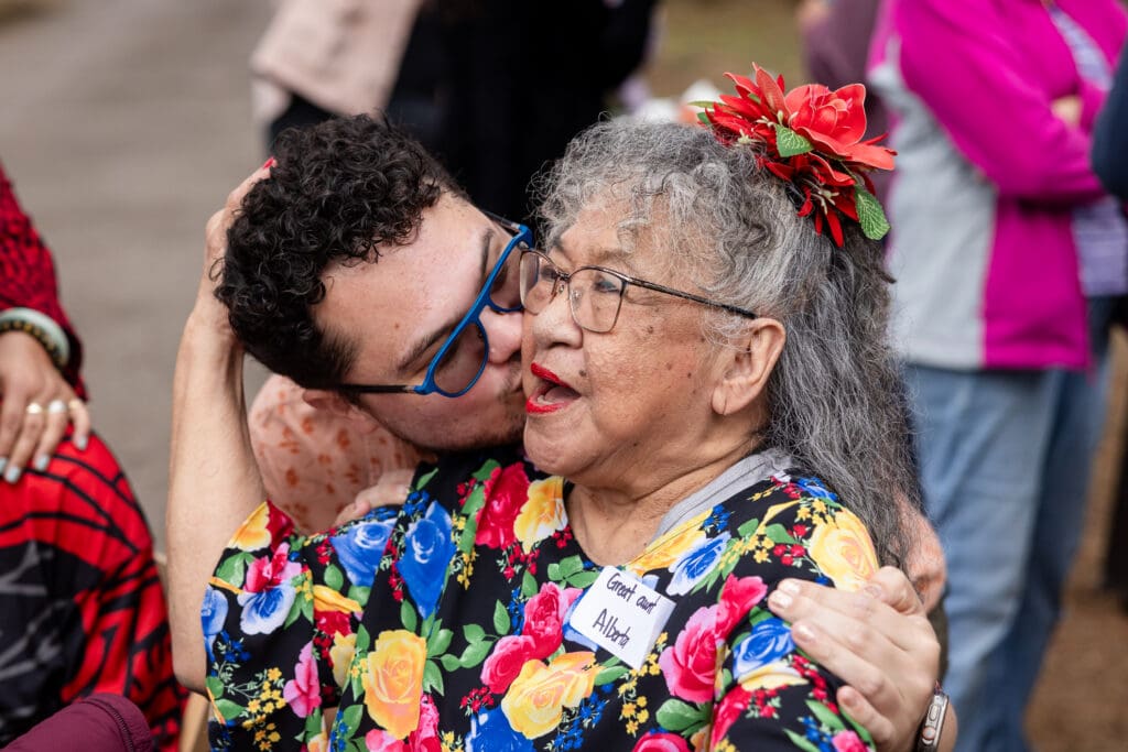 Man kissing older woman's cheek at wedding welcome dinner