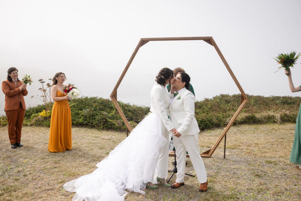 Brides kissing for their first kiss at Holly’s Ocean Meadow in Fort Bragg, CA