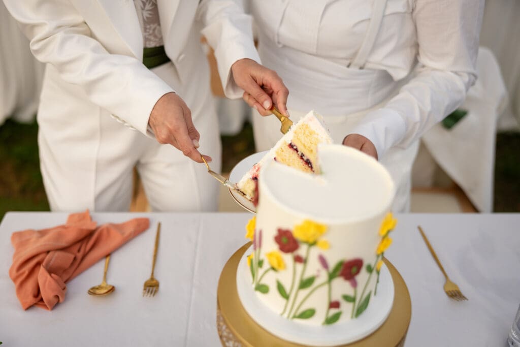 Cake cutting at wedding reception with brides at Holly’s Ocean Meadow in Fort Bragg, CA