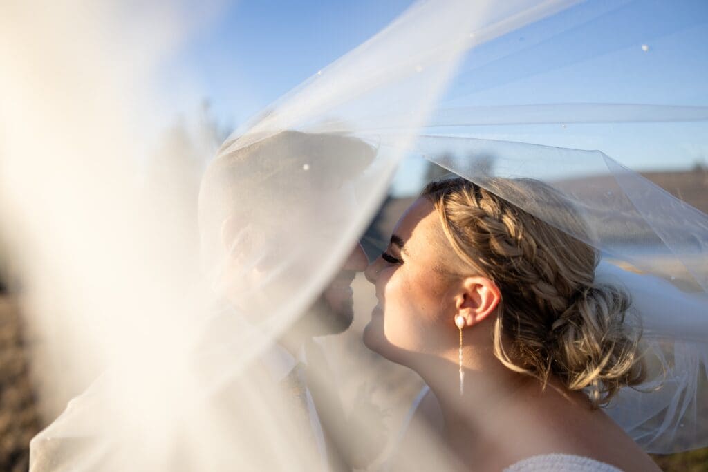 Bride and groom touching noses with veil blowing around them at Tomales wedding