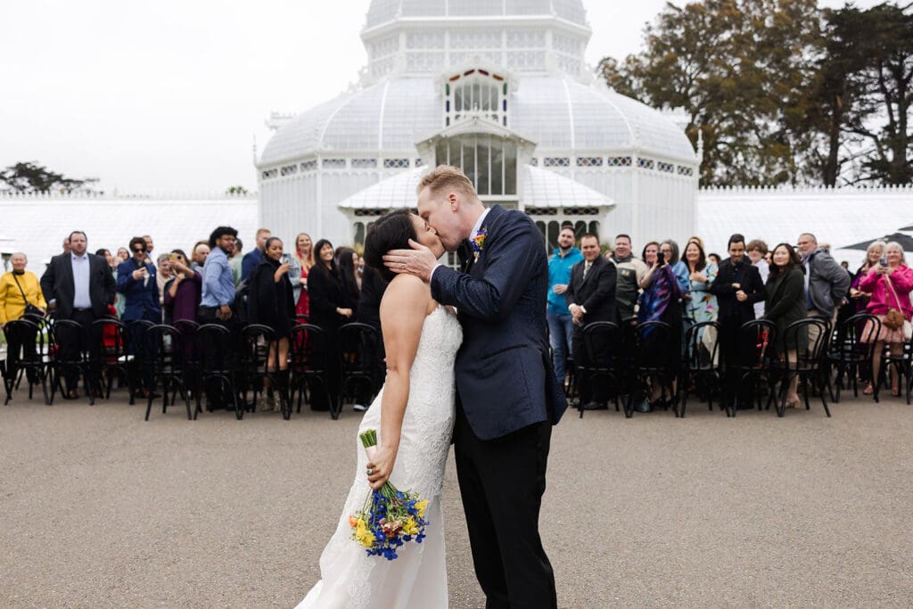 Couple kiss at San Francisco Conservatory of Flowers wedding ceremony.