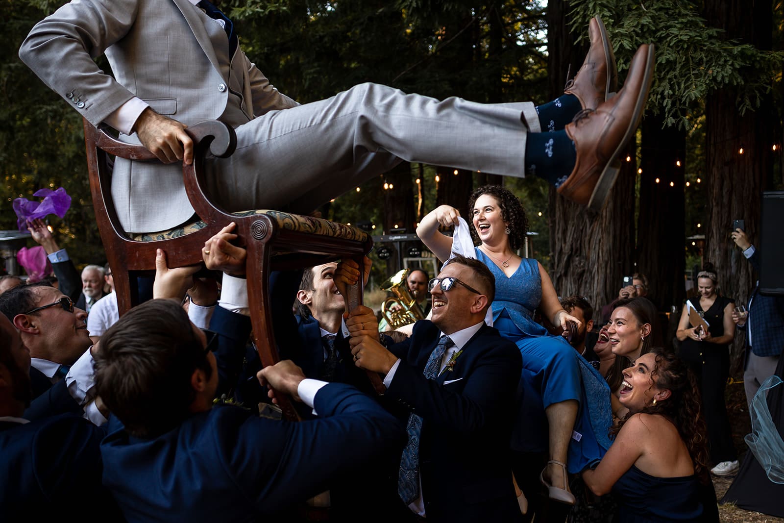 COuple in SOnoma COUnty backyard wedding are raised in chairs and dance the Hora.