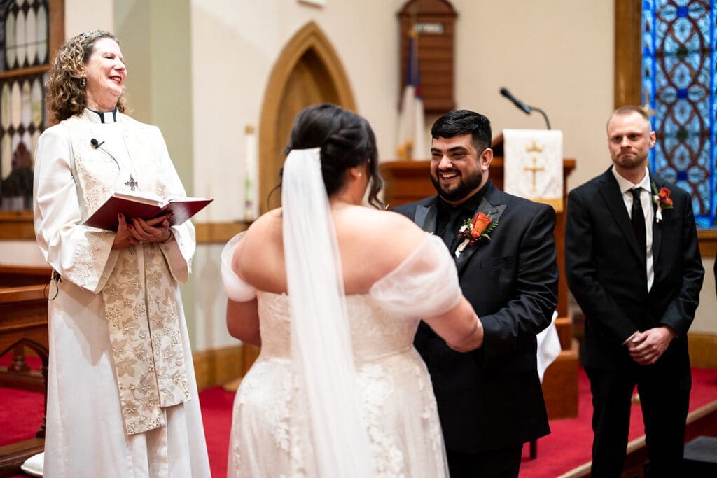 Groom smiles at bride during Elim Church Wedding ceremony.