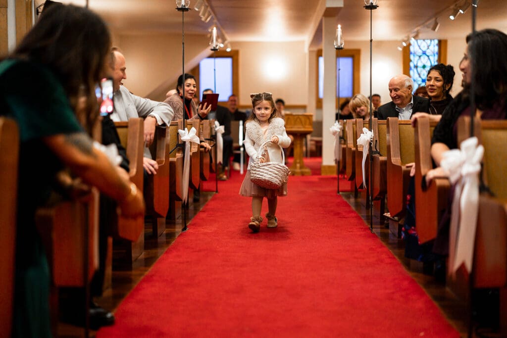 Flower girls walks down aisle at Elim Church wedding ceremony.