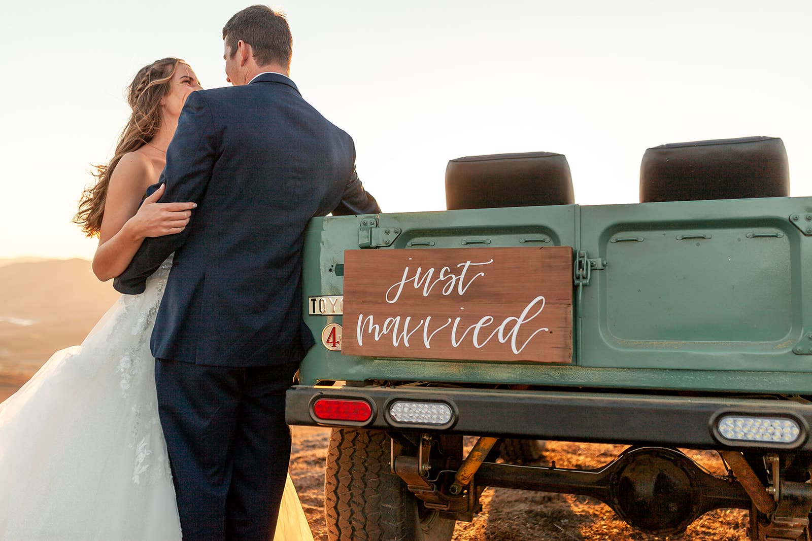 Petaluma Wedding couple embraces in golden light at the tailgate of a truck with a "Just Married" sign in the foreground.