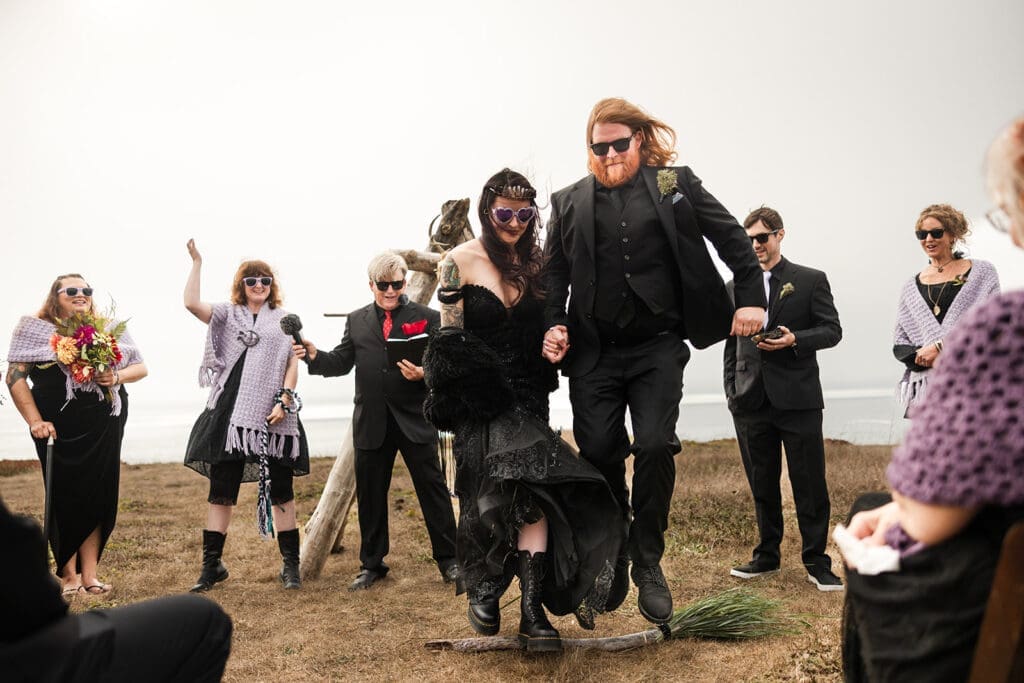 Couple jumping the handmade broom at Point Cabrillo Lighthouse wedding ceremony