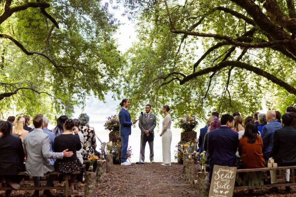 Outdoor wedding ceremony under oak trees with Leonard Lake in the background