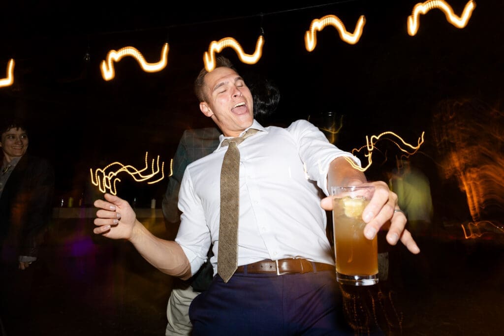 Wedding guests dancing under string lights at a Leonard Lake Reserve summer camp wedding