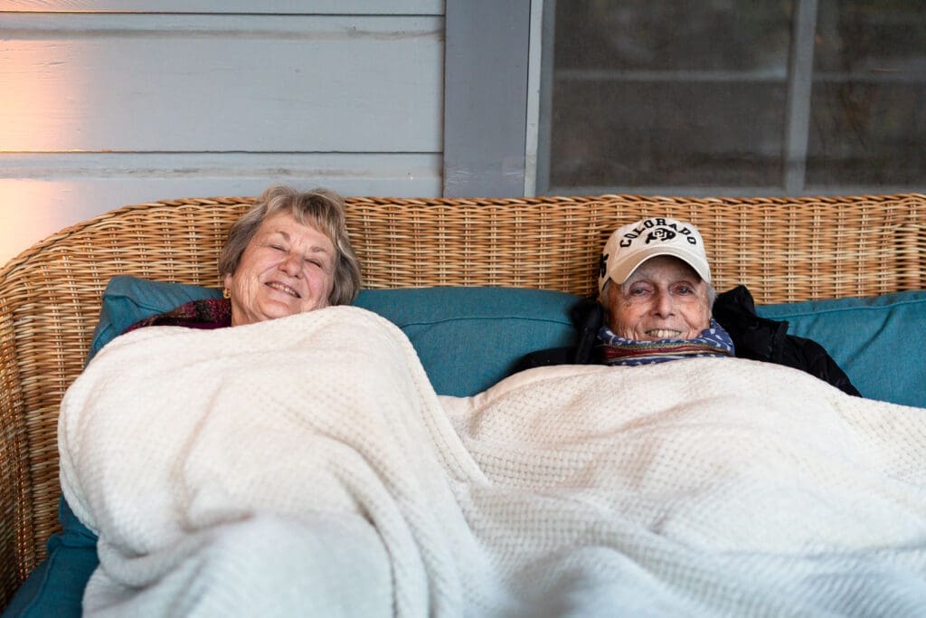 Grandparents stay warm under a blanket at a Leonard Lake Reserve summer camp wedding